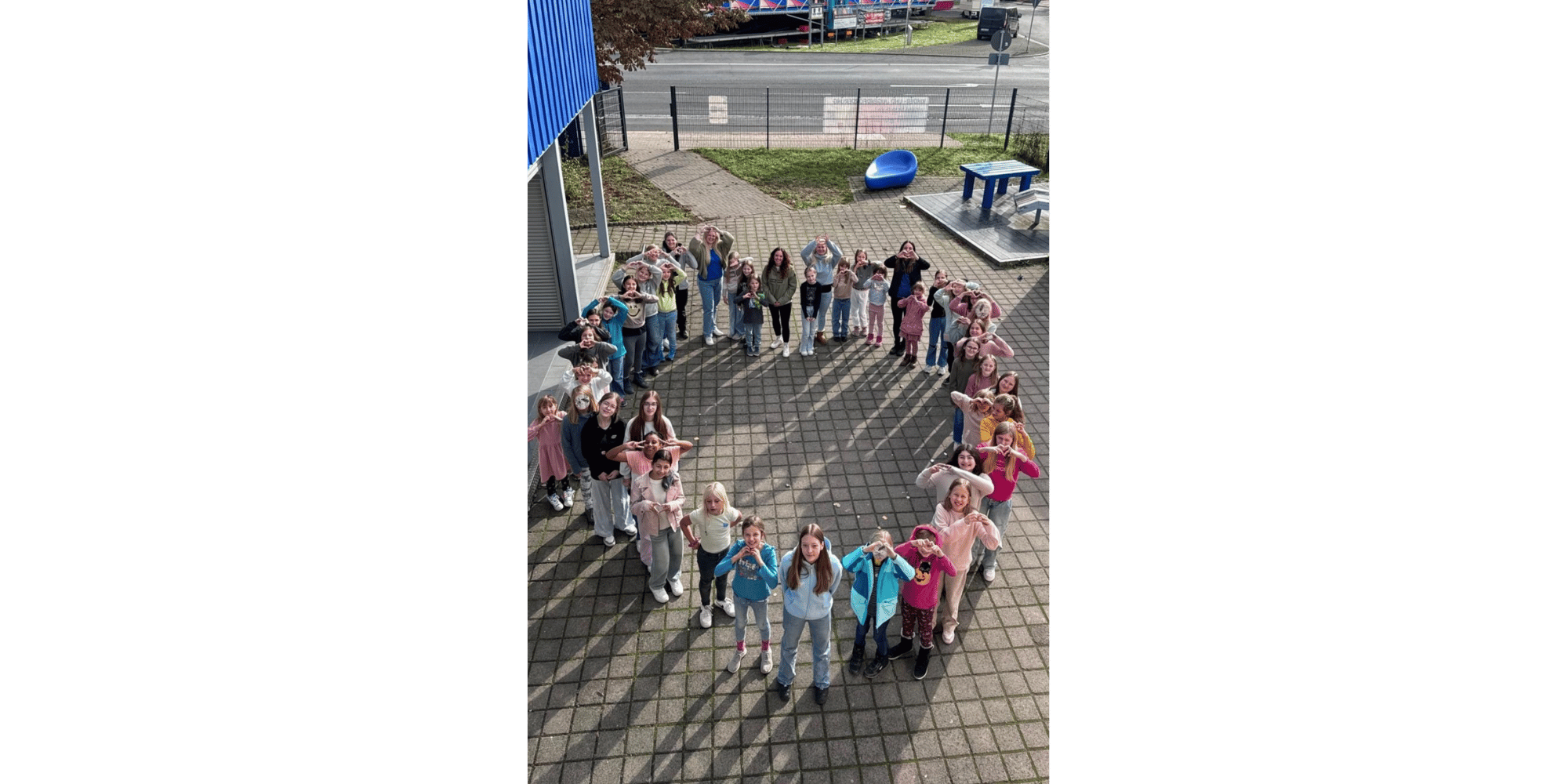 Mehrere Kinder stehend auf einem Hof in einem herzförmigen Kreis