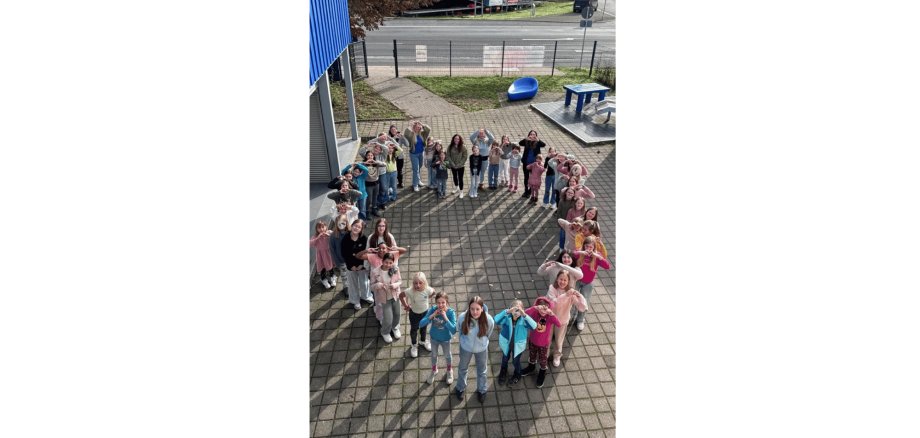 Mehrere Kinder stehend auf einem Hof in einem herzförmigen Kreis
