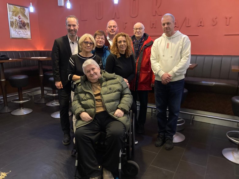 Gruppenbild zur Jubiläumsvorstellung: Bürgermeister Andreas Bär, Christa Englert, Johannes Englert, Nidderaus Seniorenberaterin Christiane Marx, Erster Stadtrat Rainer Vogel, Nicole Englert, „Regisseur“ Rainer Benthaus vom Seniorenbeirat und Theaterleiter Udo Neudecker (von links) Mehrere Personen im Foyer des Kinos