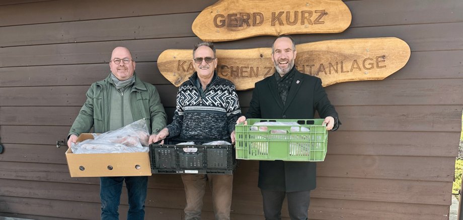 Drei Männer stehend mit je einer Kiste in der Hand