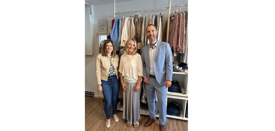 Zwei Frauen und ein Mann stehen in einem Bekleidungsgeschäft