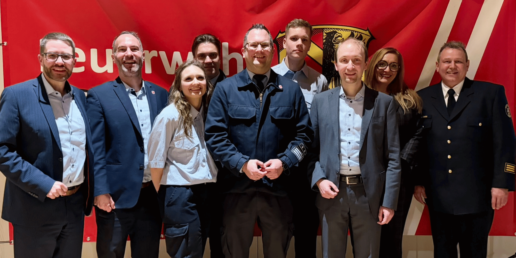 Mehrere Personen stehend vor einem roten Feuerwehrbanner