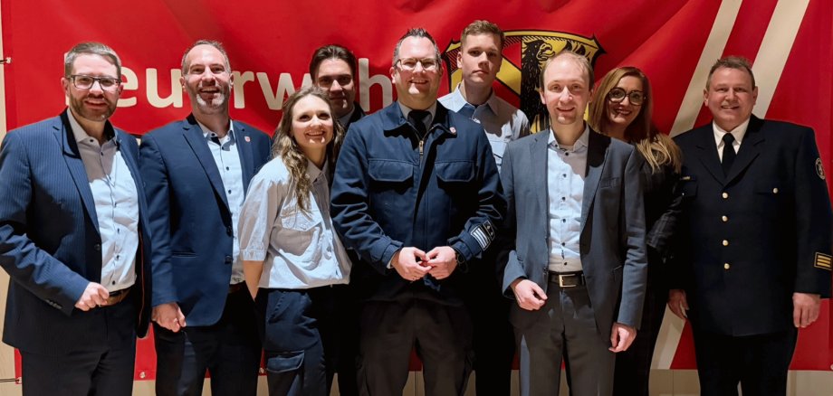 Mehrere Personen stehend vor einem roten Feuerwehrbanner