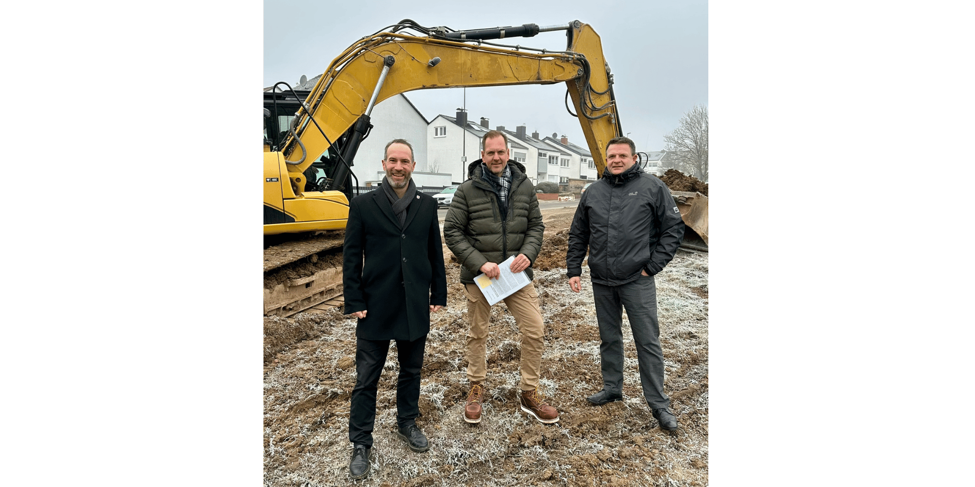 3 Männer stehend vor einem Bagger