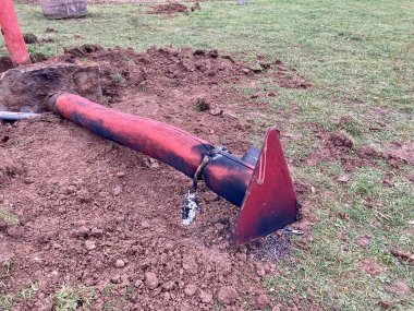 am Boden liegender Holzpfahl auf einem Feld
