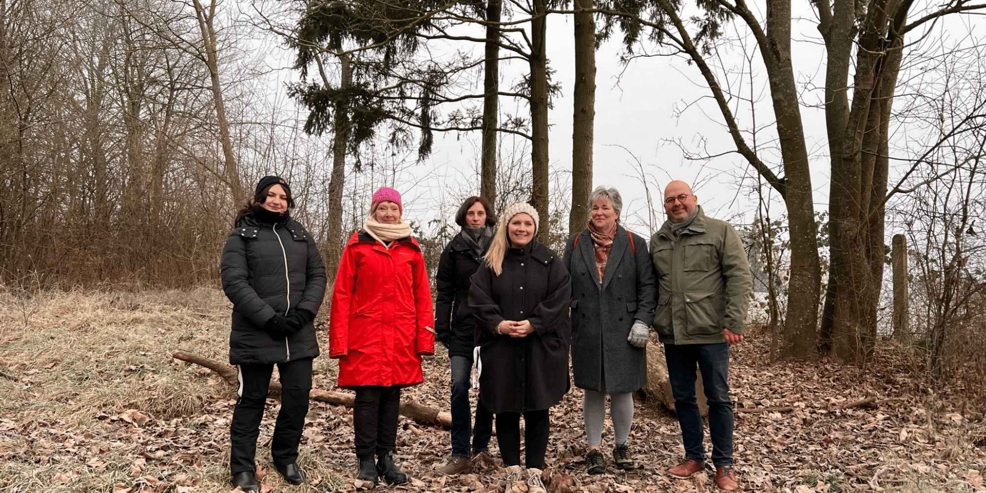 Sechs Personen stehend im Wald im Winter