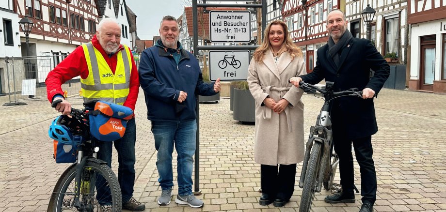 4 Personen, davon 2 mit Fahrrädern vor einem Verkehrsschild im Altstadtbereich umgeben von Fachwerkhäusern
