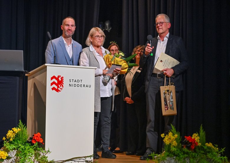 Weißes Rednerpult mit Personen stehend auf einer Bühne