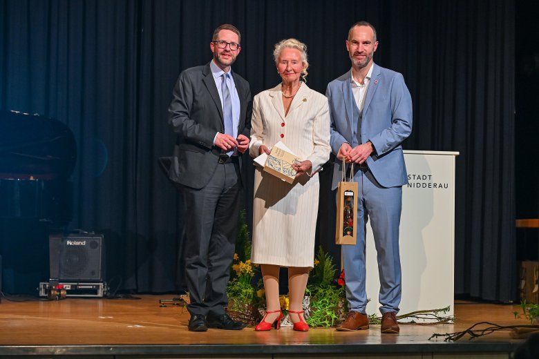 Zwei Männer und eine Frau stehend auf einer Bühne