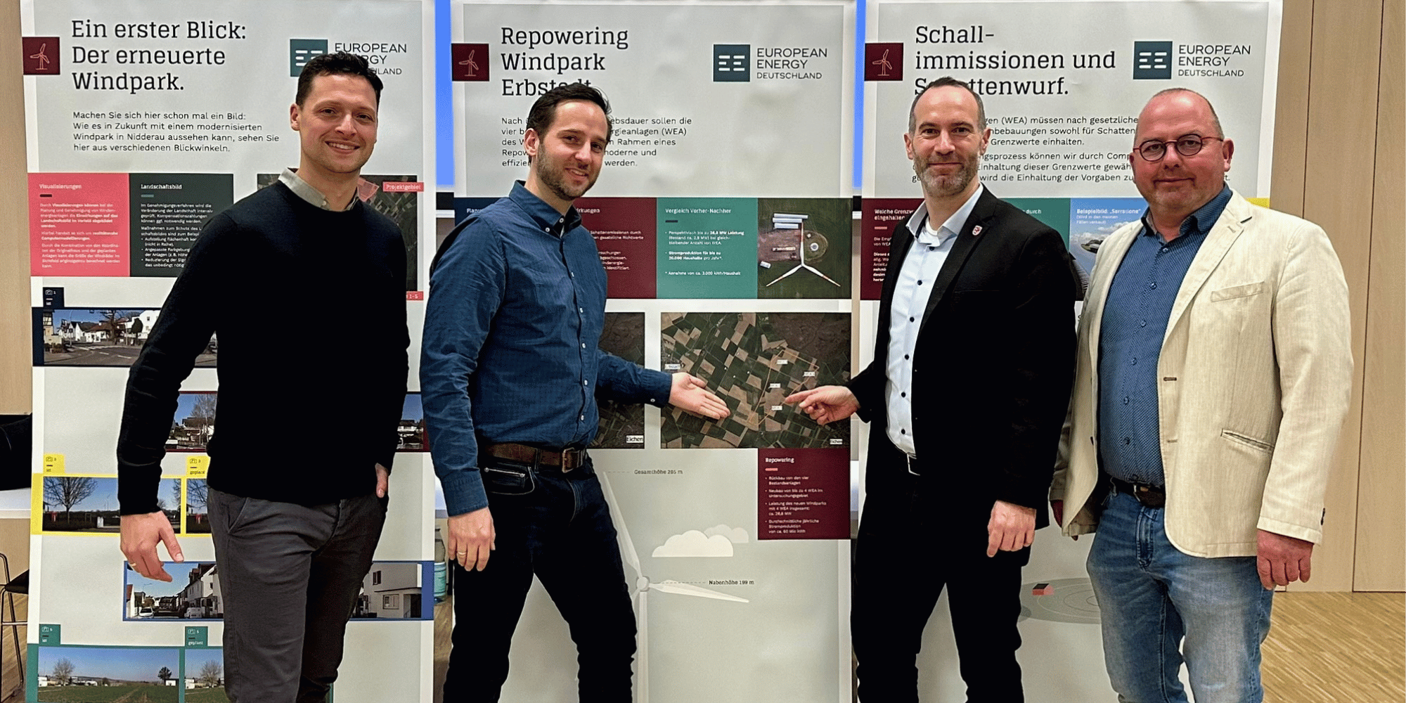 4 Männer stehend vor Roll-up-Banner zum Windpark