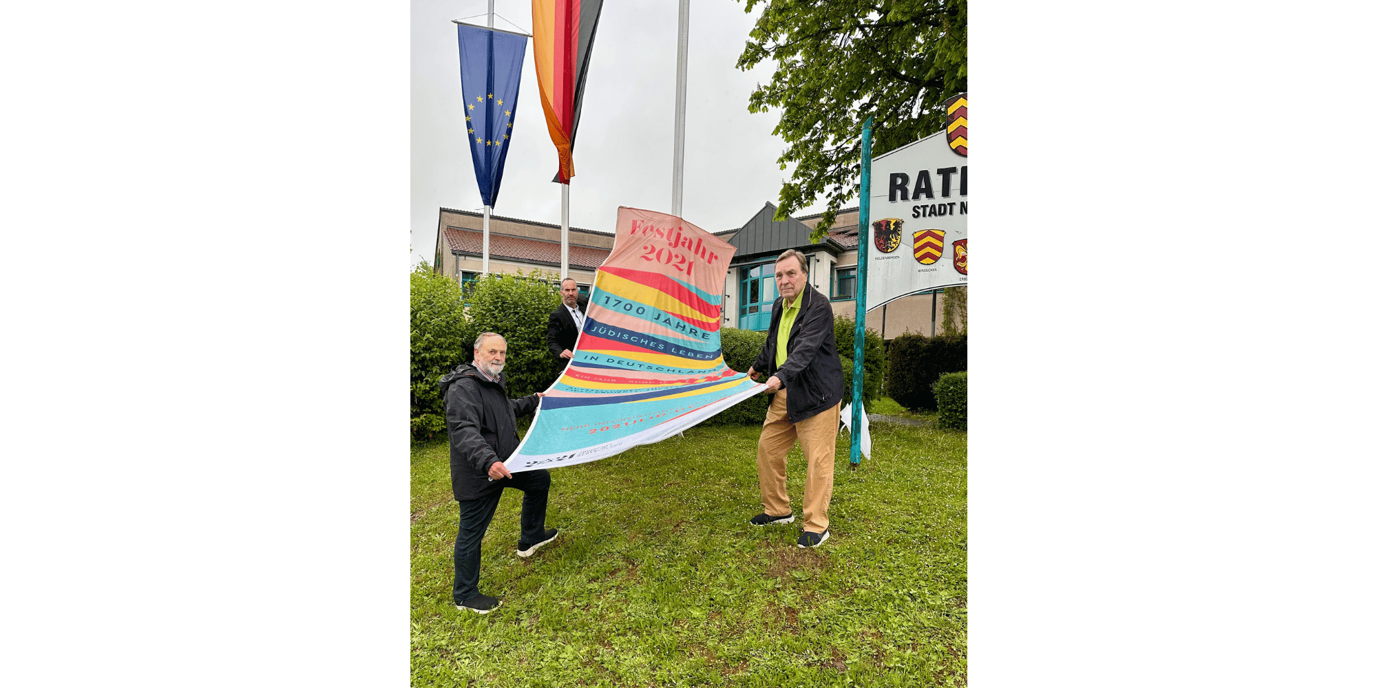 3 Männer halten eine bunte Fahne