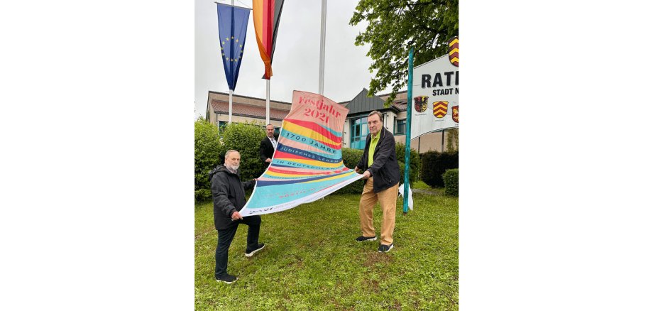 3 Männer halten eine bunte Fahne