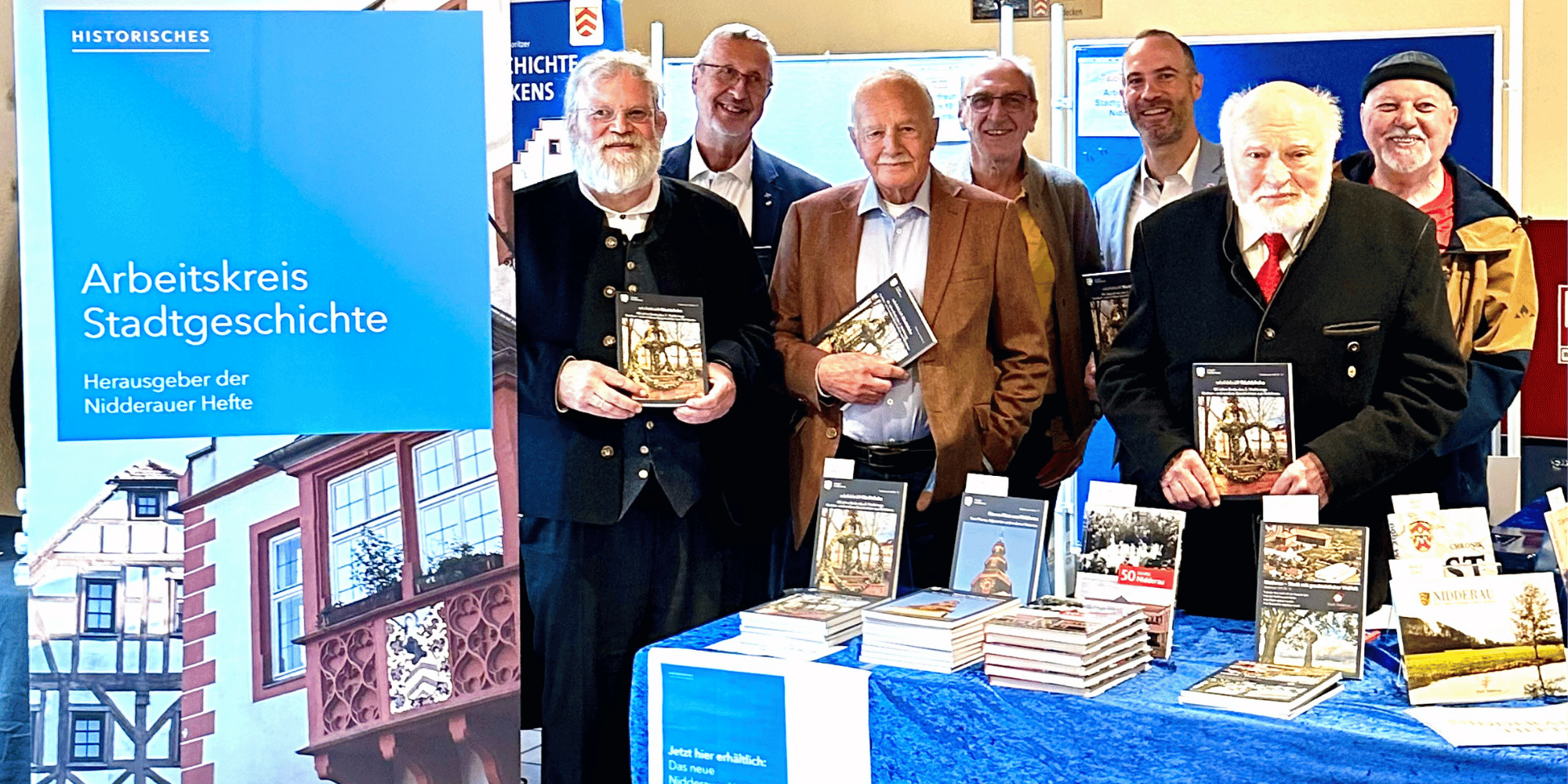 Mehrere ältere Männer stehend vor einem Verkaufsstand mit Büchern