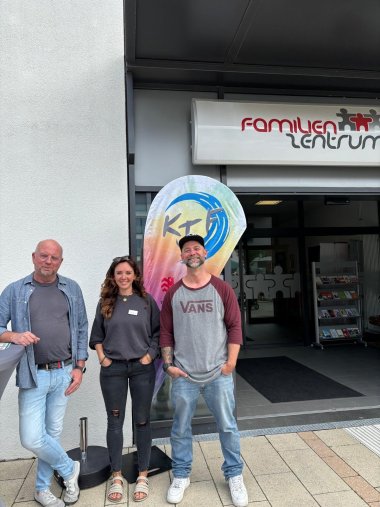 2 Männer und eine Frau stehend vor einem Gebäude