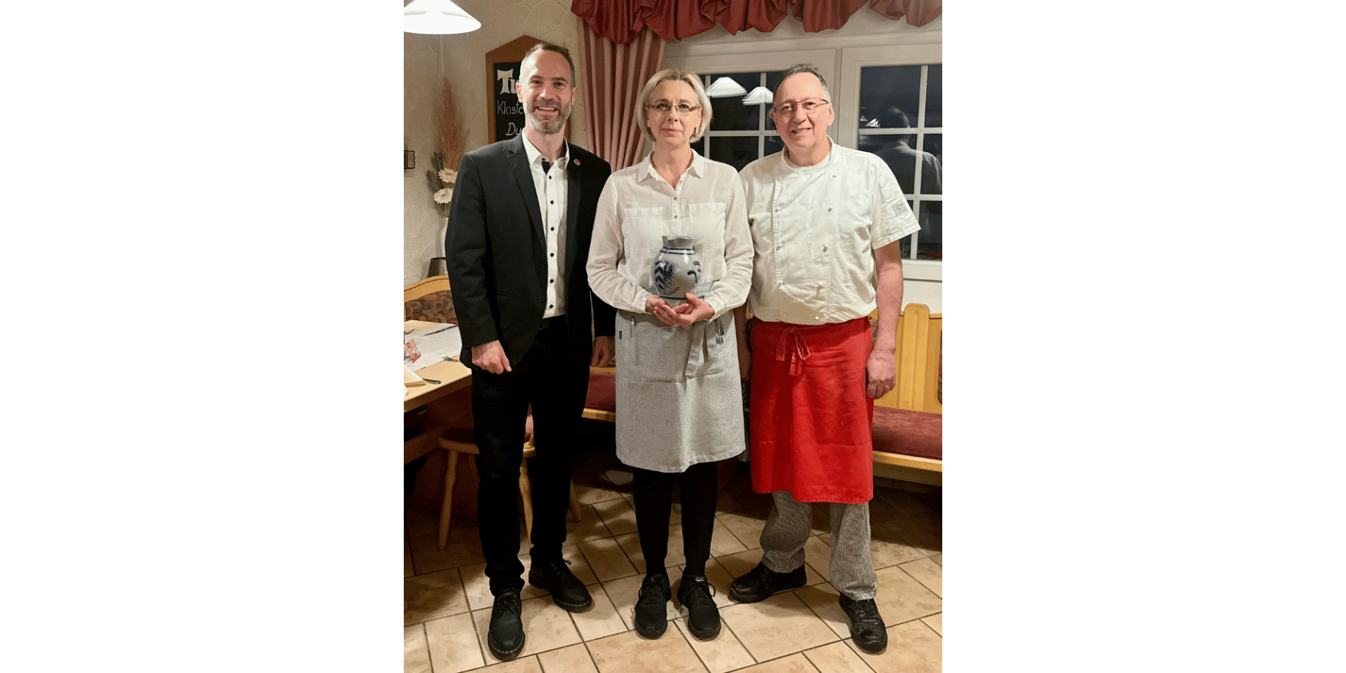 Zwei Männer und eine Frau stehend vor der Theke in einer Gaststätte