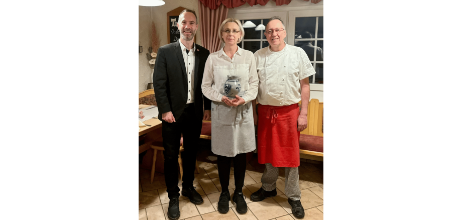 Zwei Männer und eine Frau stehend vor der Theke in einer Gaststätte