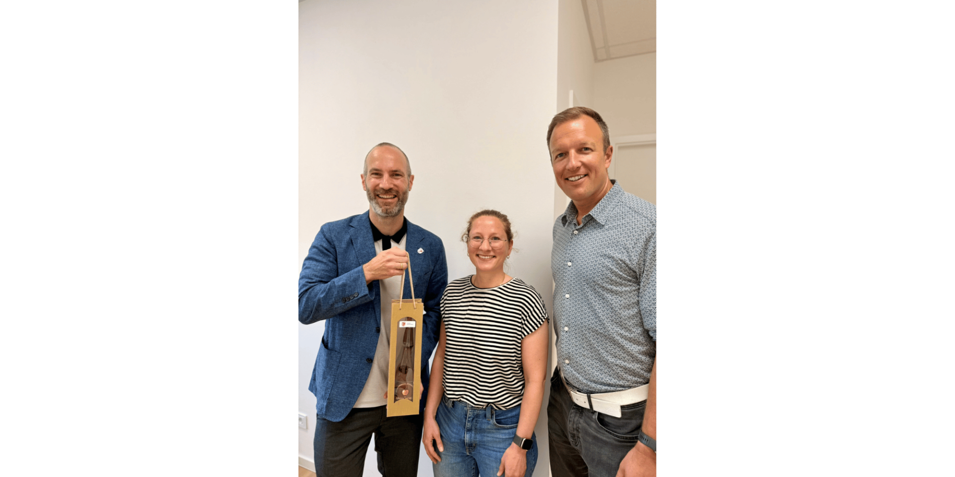 Eine Frau und zwei Männer stehend und lächelnd