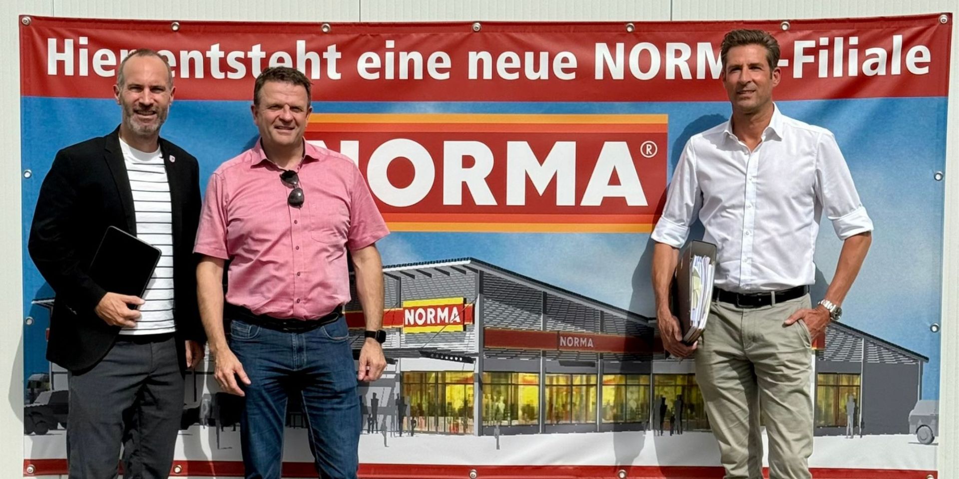 Drei Männer stehen vor Werbebanner