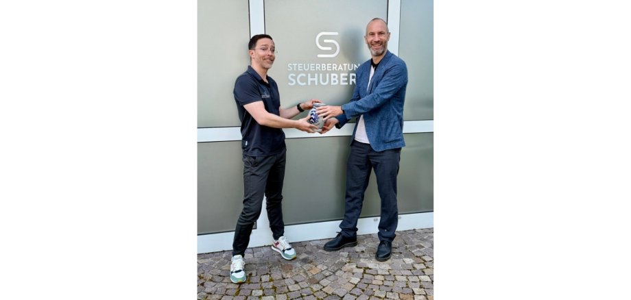 Zwei Männer stehend. Der eine überreicht dem anderen einen hessischen Krug (Bembel).