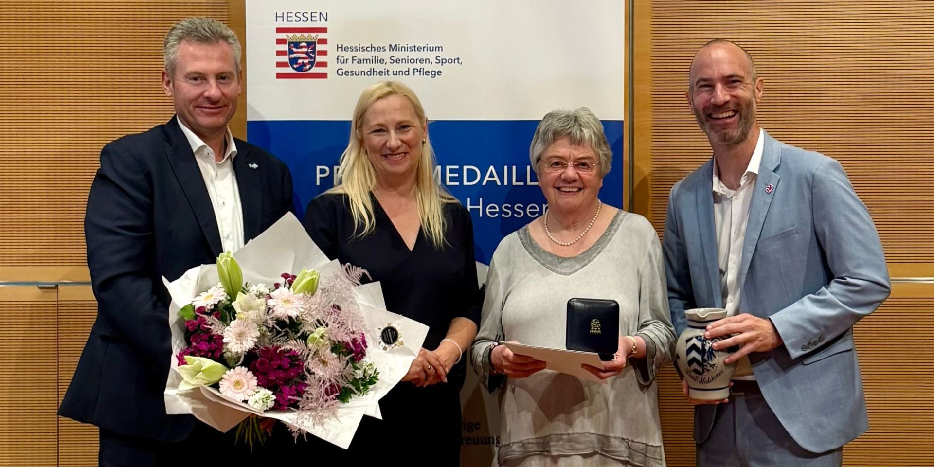 Zwei Frauen und zwei Männer stehen vor einem Banner