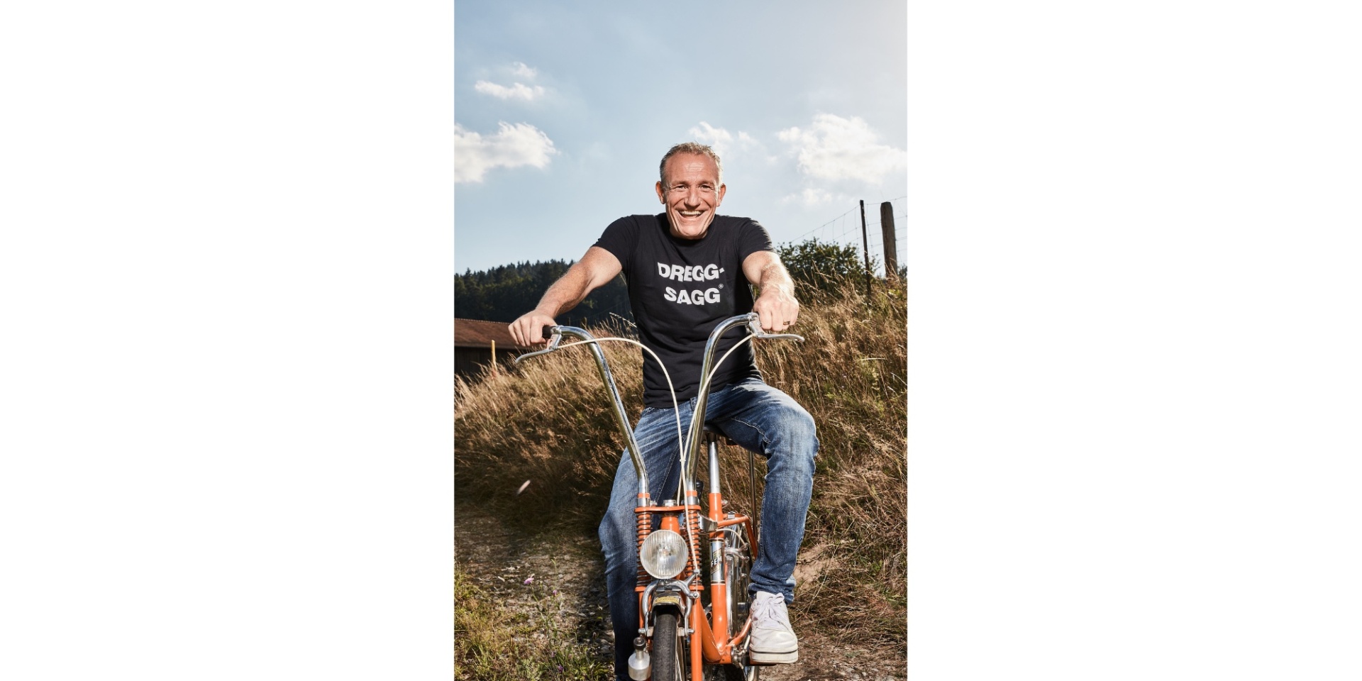 Mann auf einem Moped sitzend vor einem Kornfeld