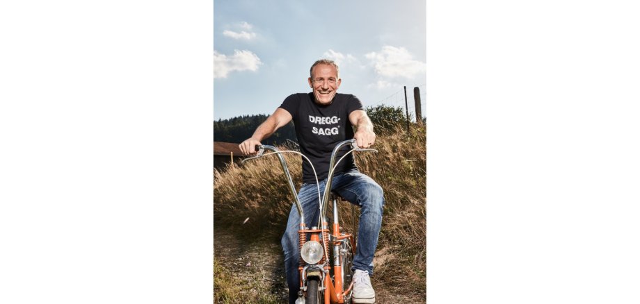 Mann auf einem Moped sitzend vor einem Kornfeld