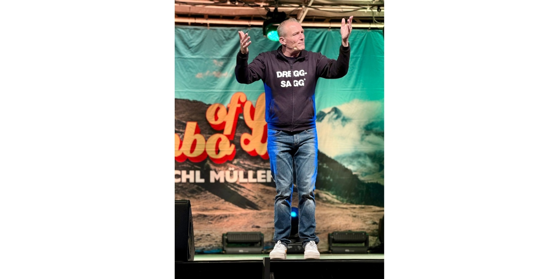 Mann in einer Sweatjacke mit der Aufschrift "Dreggsagg" auf einer Bühne