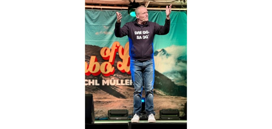 Mann in einer Sweatjacke mit der Aufschrift "Dreggsagg" auf einer Bühne