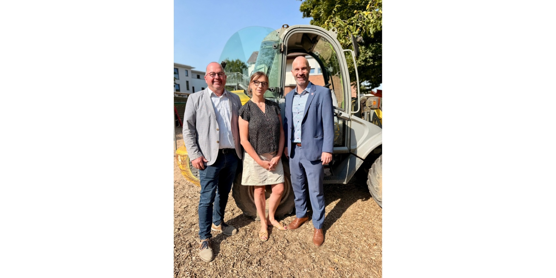 Zwei Männer und eine Frau stehend in einer im Umbau befindlichen Außenanlage eines Kindergartens