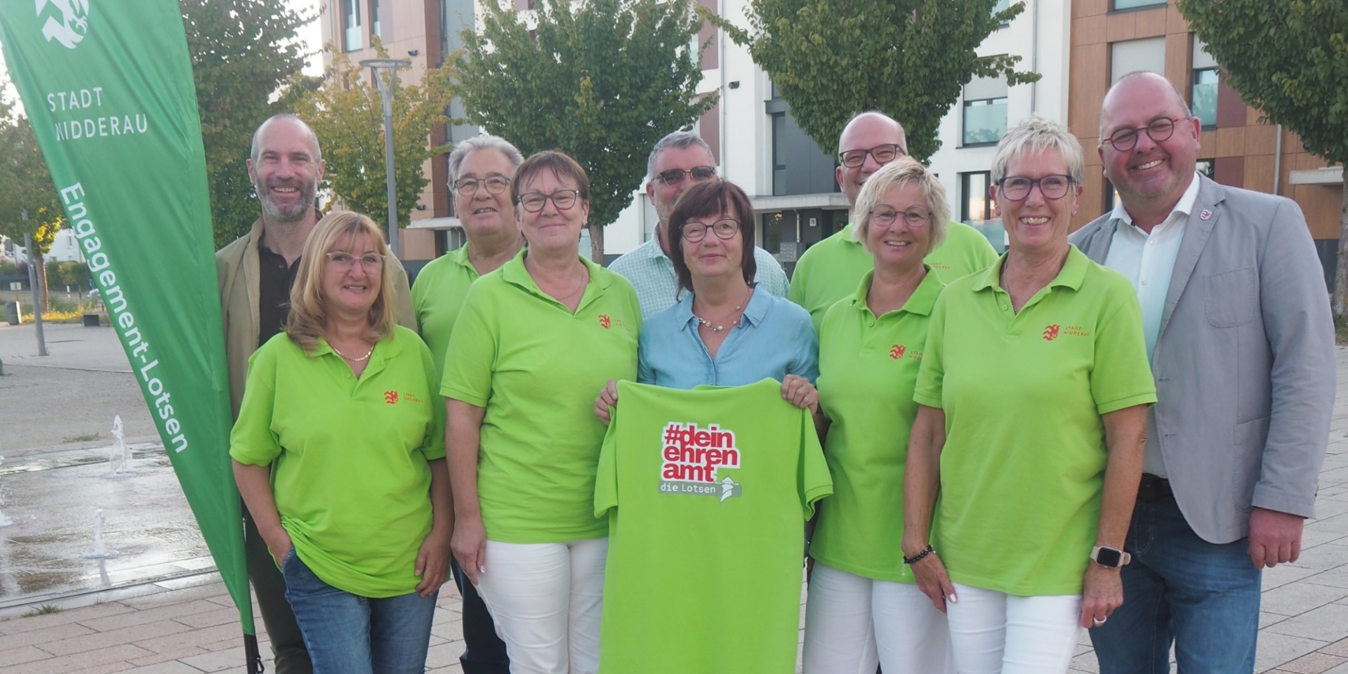 Mehrere Personen auf dem Stadtplatz stehend. Ein paar tragen neongrüne T-Shirts