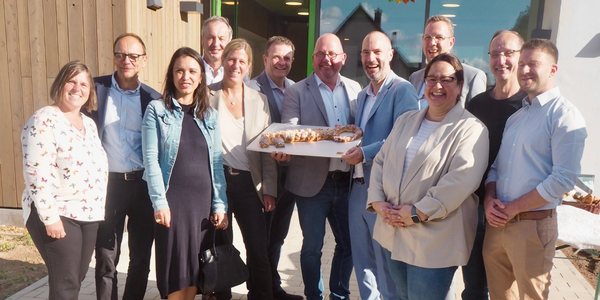 Mehrere Personen stehen zusammen vor einem neu gebauten Gebäude