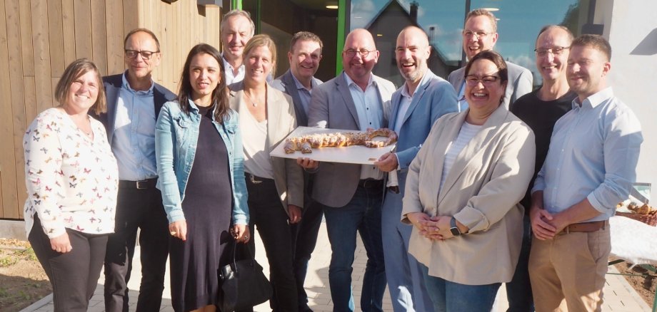 Mehrere Personen stehen zusammen vor einem neu gebauten Gebäude