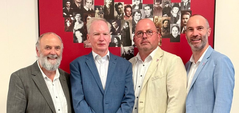 Vier Männer stehend vor einem roten Hintergrund