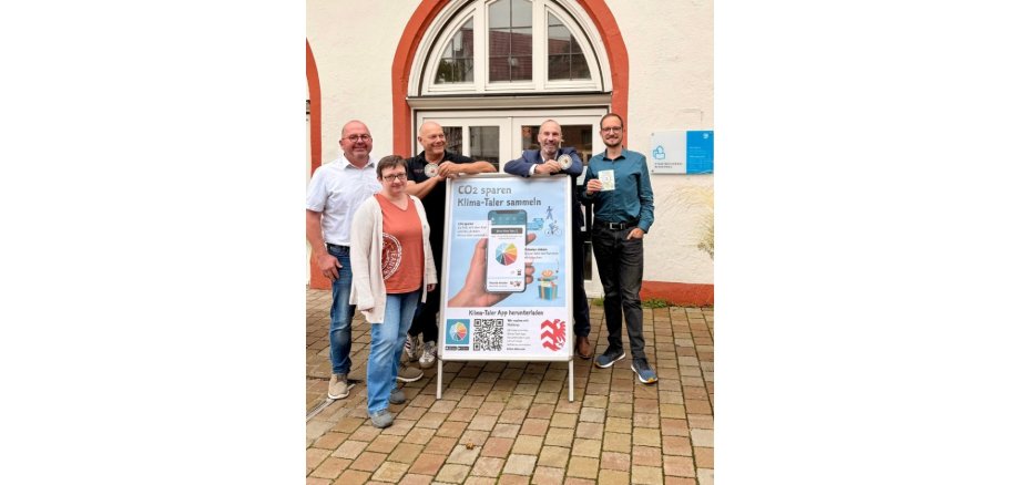 Eine Frau und vier Männer stehend um eine Reklametafel