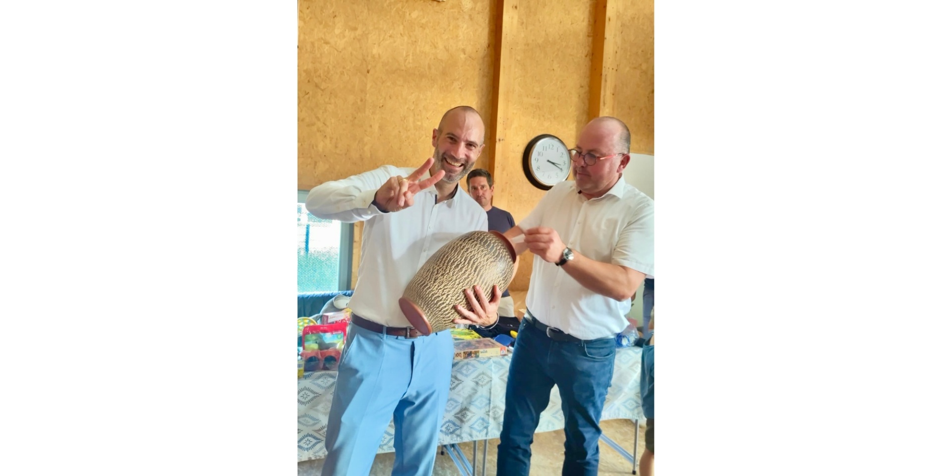 Zwei Männer stehend. Der eine Mann hält eine große Vase in der Hand