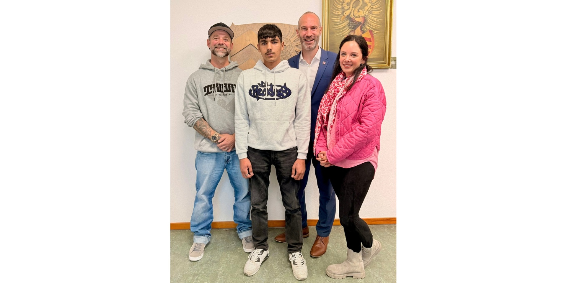 Zwei Männer, ein junger Heranwachsender und eine Frau stehend.