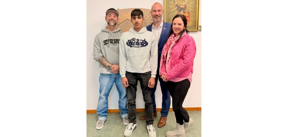 Zwei Männer, ein junger Heranwachsender und eine Frau stehend.