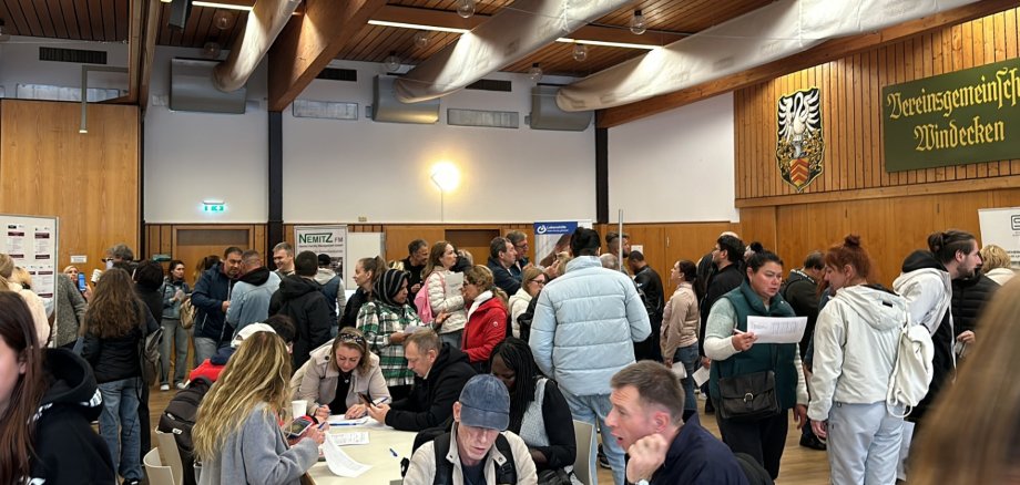 Viele Menschen stehend oder sitzend in einer Bürgerhalle