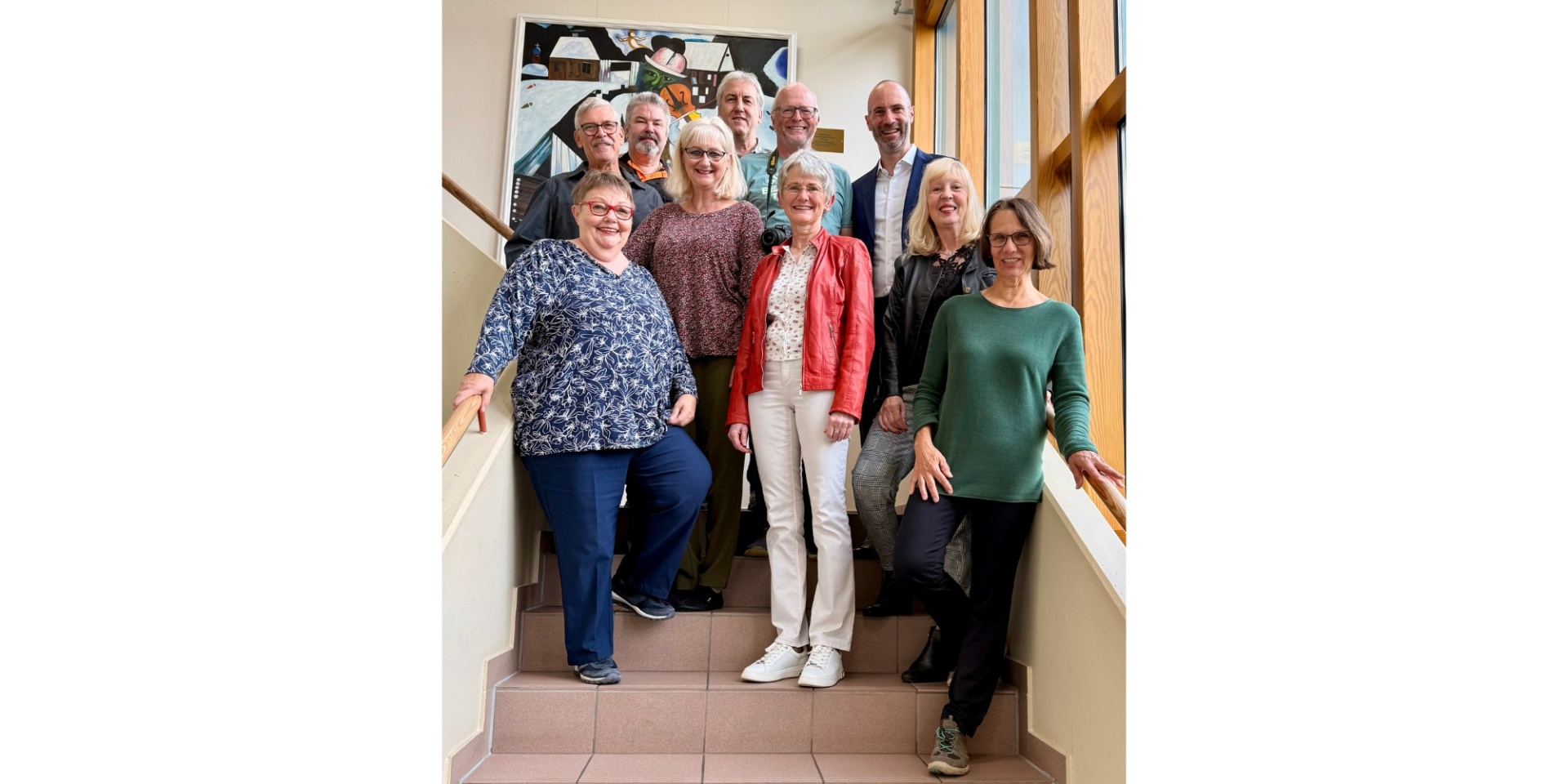 Fünf Frauen und fünf Männer stehend auf einer Treppe in einem Treppenhaus.