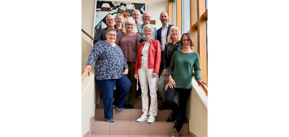 Fünf Frauen und fünf Männer stehend auf einer Treppe in einem Treppenhaus.