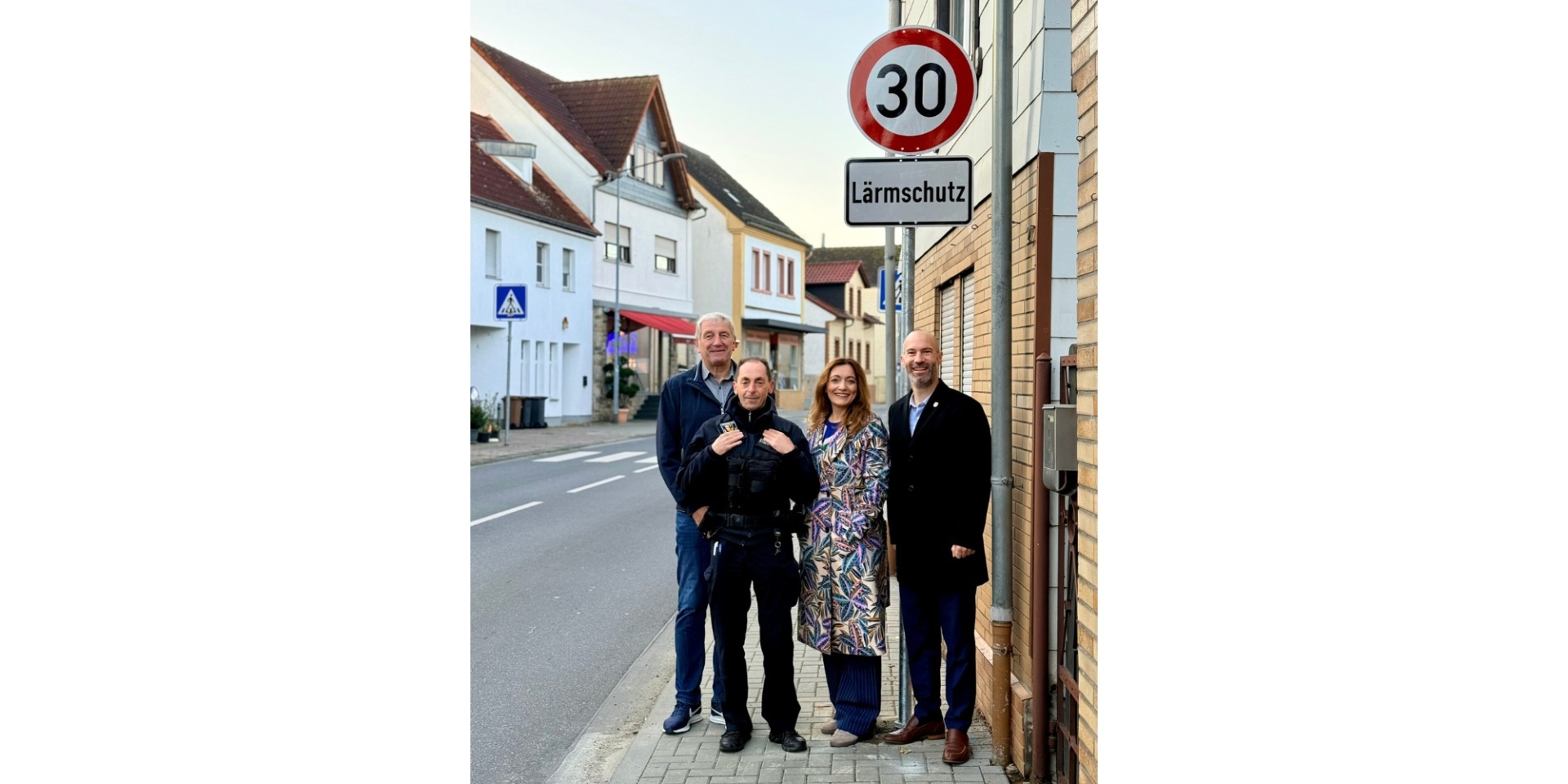 Eine Frau und drei Männer stehend vor einem Tempo-30-Schild mit Zusatzschild "Lärmschutz".
