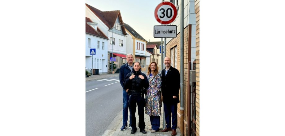 Eine Frau und drei Männer stehend vor einem Tempo-30-Schild mit Zusatzschild "Lärmschutz".
