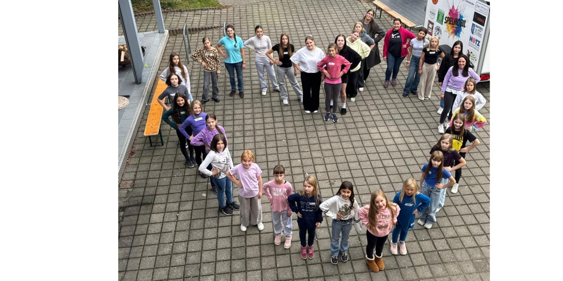 Mädchengruppe aufgestellt in Herzform aus Vogelperspektive aufgenommen. 