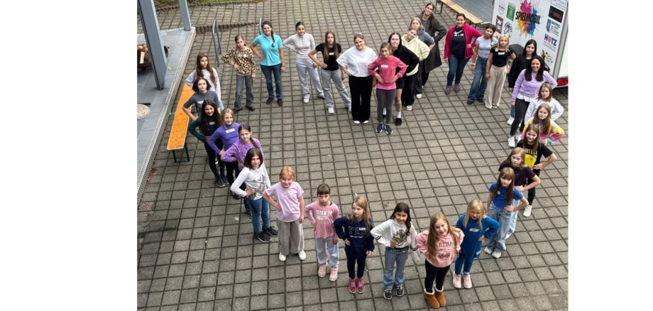 Mädchengruppe aufgestellt in Herzform aus Vogelperspektive aufgenommen.