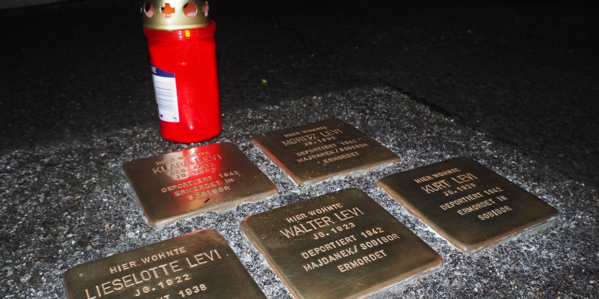 Ansicht Stolpersteine  mit einer roten Grabkerze
