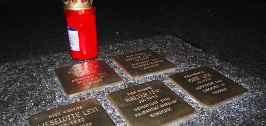 Ansicht Stolpersteine  mit einer roten Grabkerze