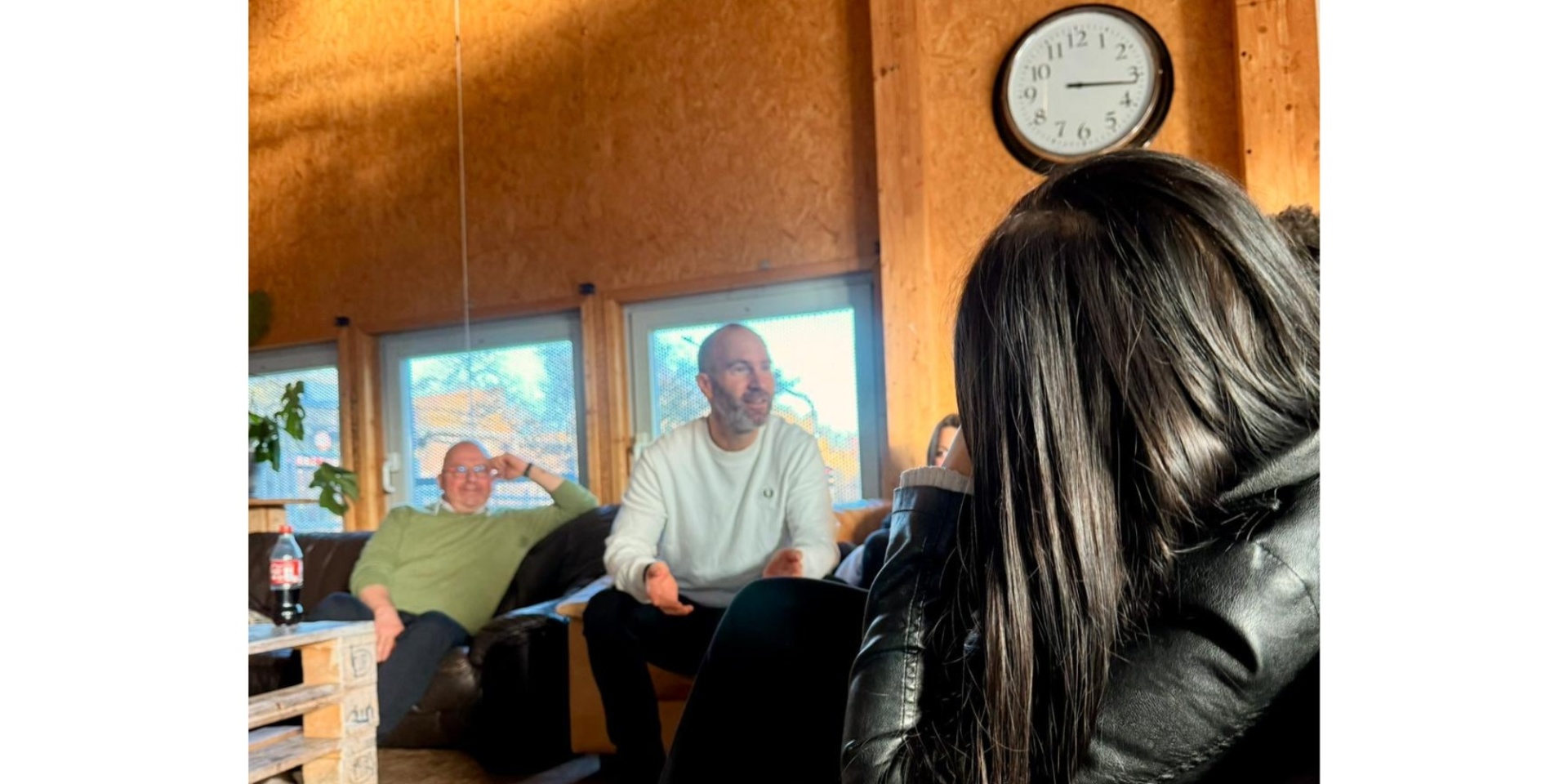 Zwei Männer sitzend mit einer Gruppe junger Erwachsener