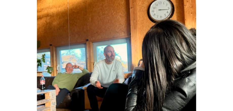 Zwei Männer sitzend mit einer Gruppe junger Erwachsener