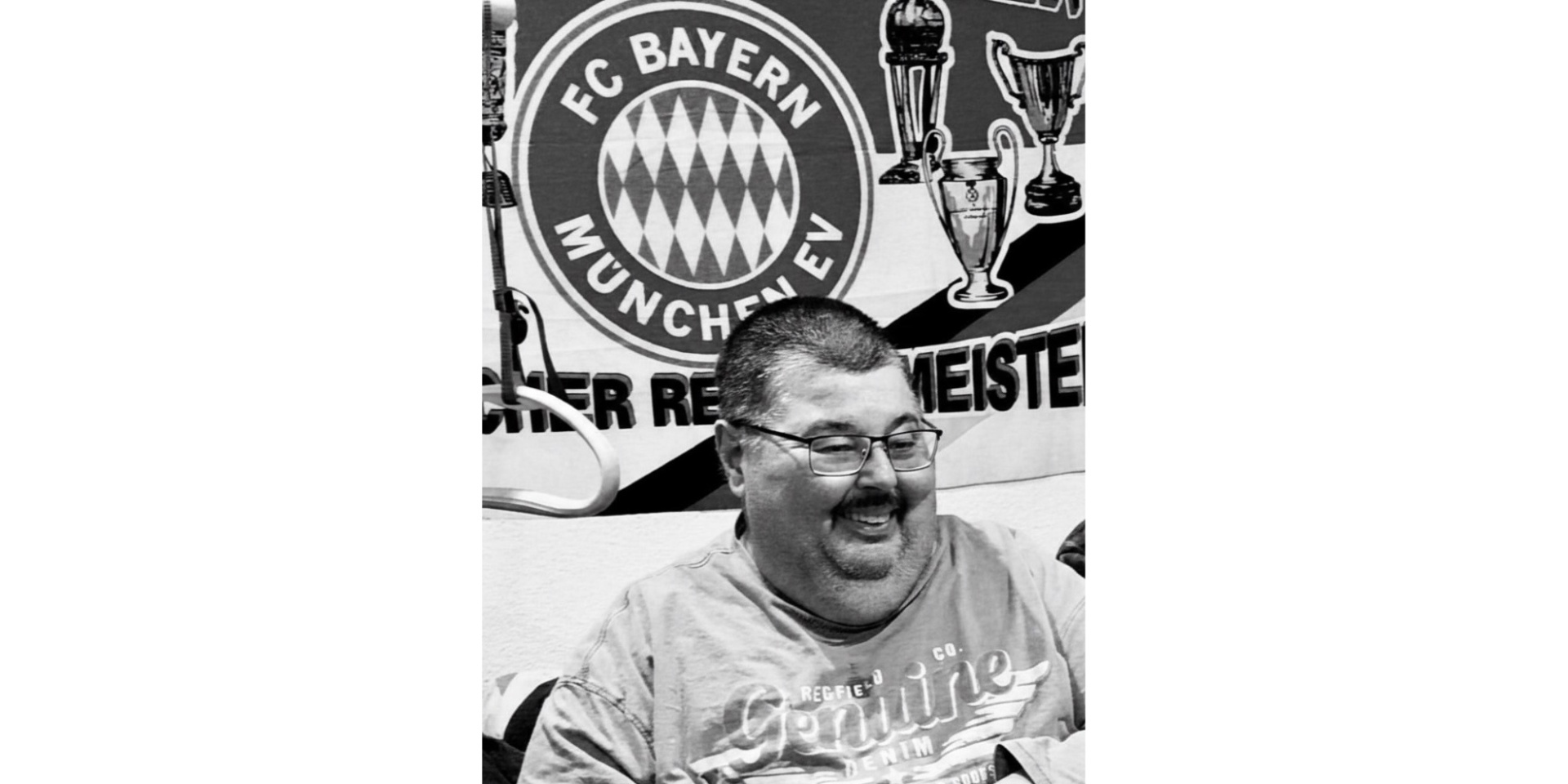 Schwarz-weiß Foto von einem Mann sitzend vor einem Fußball-Vereinslogo