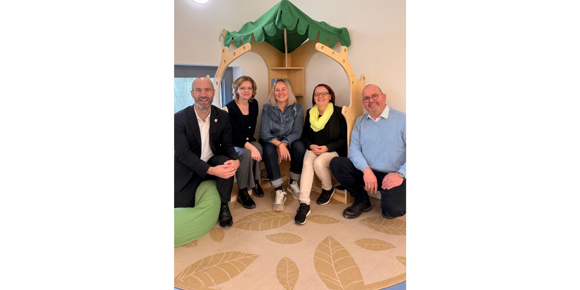 Zwei Männer und drei Frauen sitzen nebeneinander in einer Kita